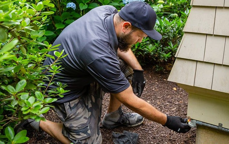 technician from Tim's Pest Control inspecting a house